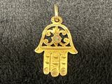 un gros plan d'un petit pendentif hamsa en or sur une surface noire