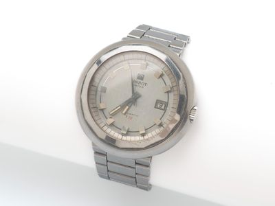 une montre argentée posée sur une surface blanche, sur fond blanc