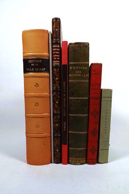 several old books are stacked on top of each other on a white surface