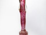 sculpture of a woman in a pink dress standing on a wooden block