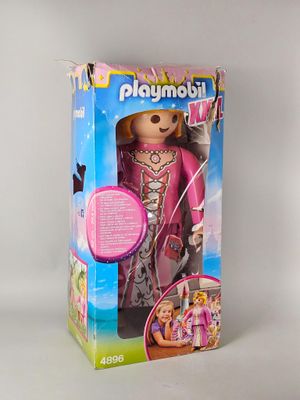 poupée dans la boîte d'une poupée Playmobil, vêtue d'une tenue rose et de chaussures roses