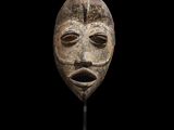 une image représentant un masque posé sur un support, sur fond noir