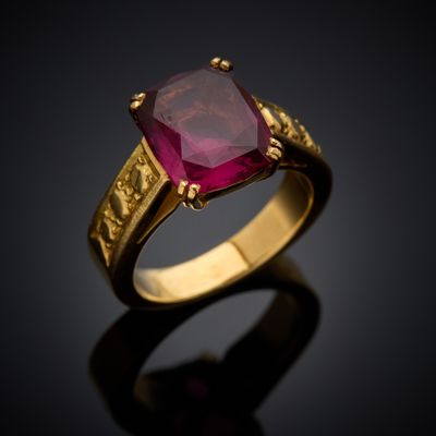 a gold ring with a ruby stone in the center