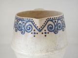 a white vase with blue designs on it on a table