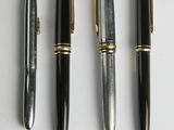 quatre types de stylos différents alignés sur une surface blanche
