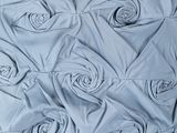 a bed with a blue and white comforter with roses on it