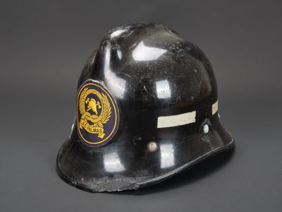 un vieux casque de pompier noir orné d'un emblème représentant un lion