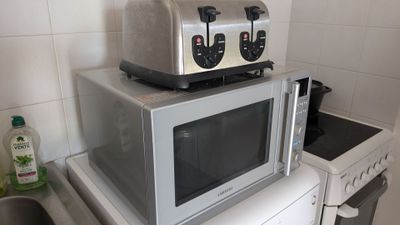 un four grille-pain posé sur un micro-ondes dans une cuisine