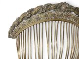 a gold comb that is sitting on a white surface