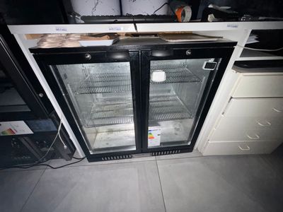 a refrigerator with two glass doors in the middle of a kitchen