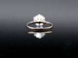 a close up of a diamond engagement ring on a reflective surface