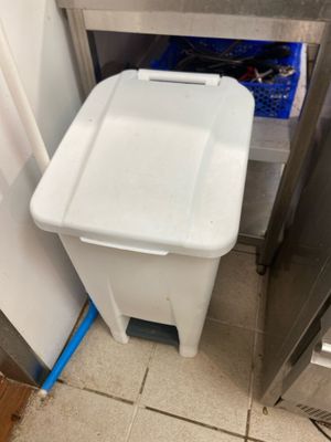 a white trash can sitting in the corner of a kitchen