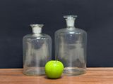 two empty glass bottles with a green apple on the table