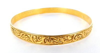 a close up of a gold bracelet on a white surface