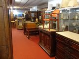 a room filled with lots of antique furniture and glass cases