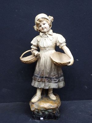 une statue représentant une jeune fille avec un panier, assise sur un rocher