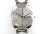 une montre en argent posée sur une surface blanche