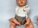 a small doll sitting next to a small doll on a white surface