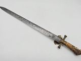 a close up of a knife with a wooden handle on a white surface