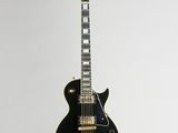 a black electric guitar hanging from a white wall