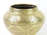 a gold vase that is sitting on a white surface