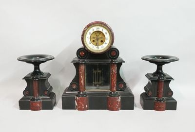 une horloge posée sur une table, à côté de deux bougies