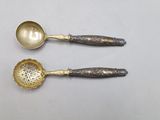 two silver spoons and a silver spoon on a white surface