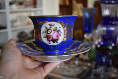 a person holding a cup and saucer in their hand