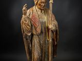 une statue représentant un homme en robe tenant un bâton