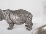a rhino figurine sitting on a table next to a glass