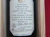 une bouteille de vin dans un coffret en bois, posée sur un support rouge