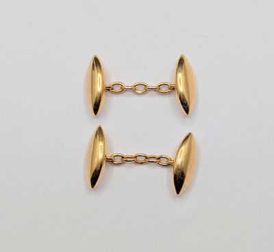 une paire de boutons de manchette plaqués or sur fond blanc