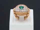 a close up of a gold ring with a green stone and diamonds