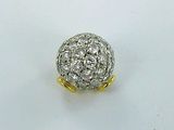 une photo d'une bague avec une boule en diamant posée sur une surface blanche