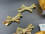 three pieces of gold bow brooches on a table