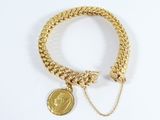 Gros plan sur un bracelet en or orné d'une pièce de monnaie