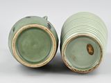 two green vases sitting side by side on a white surface