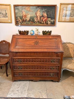 un bureau et une chaise en bois dans une pièce où sont accrochés des tableaux au mur