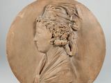 a close up of a clay medallion with a woman ' s head