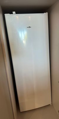 a white refrigerator in the corner of a small room