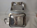 two silver plated dishes sitting on top of a clear glass table