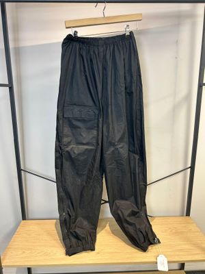un pantalon en cuir noir suspendu à un porte-vêtements devant un mur blanc