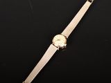 a gold watch on a black surface with a black background