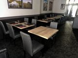 tables and chairs in a restaurant with pictures hanging on the wall