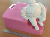une petite statue blanche représentant un homme assis sur une boîte rose