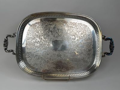 un plat ancien en argent avec des poignées, sur fond gris
