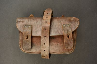 an old leather bag with two straps hanging on a wall