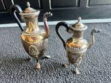 deux théières en argent posées par terre l'une à côté de l'autre
