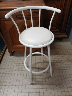 a white bar stool with a white seat on a tiled floor