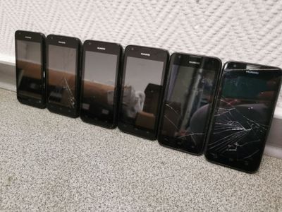 six cell phones are lined up in a row on the floor